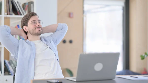 Glücklicher Mann mit Brille und Laptop entspannt im Büro — Stockfoto