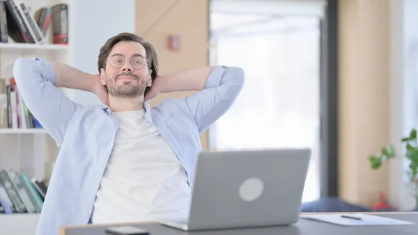 Человек в очках с ноутбуком сидит и расслабляется — стоковое фото