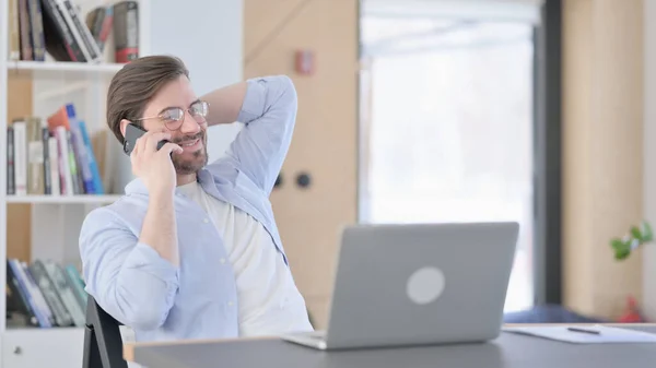 Uomo in occhiali con computer portatile utilizzando Smartphone in ufficio — Foto Stock