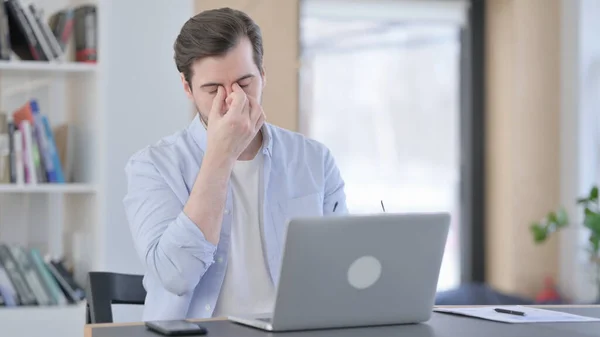 Man in glazen met laptop die hoofdpijn heeft — Stockfoto