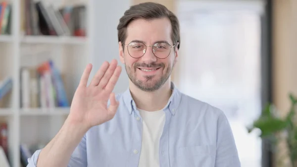 Retrato del hombre con gafas ondeando, dando la bienvenida — Foto de Stock