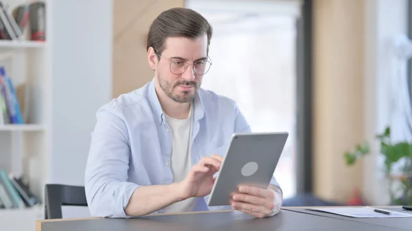 Hombre atractivo en gafas usando tableta en la oficina — Foto de Stock