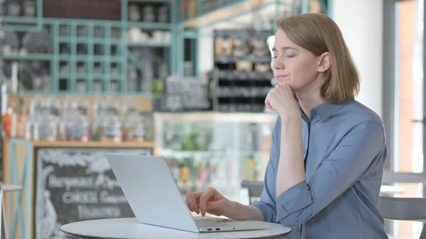 Mujer joven pensando mientras usa el ordenador portátil en Café — Foto de Stock