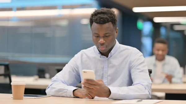 Atraktivní africký podnikatel používající Smartphone v kanceláři — Stock fotografie