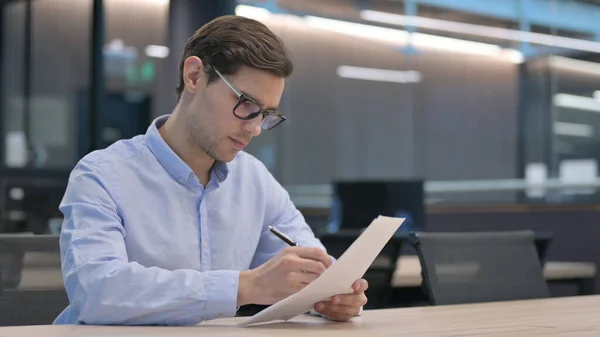 Молодой человек читает документы на работе — стоковое фото