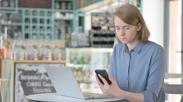 Mladá žena pracuje na Smartphone a notebook v kavárně — Stock fotografie