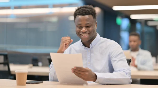 Αφρικανός επιχειρηματίας γιορτάζει την επιτυχία ενώ διαβάζει τα έγγραφα — Φωτογραφία Αρχείου