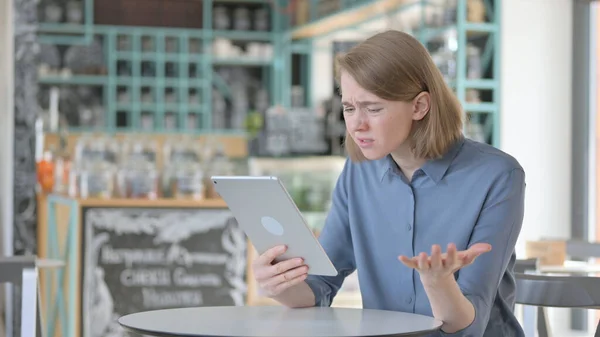 Mladá žena reaguje na ztrátu na tabletu v kavárně — Stock fotografie