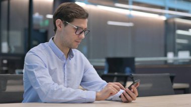 Genç adam akıllı telefon kullanıyor.