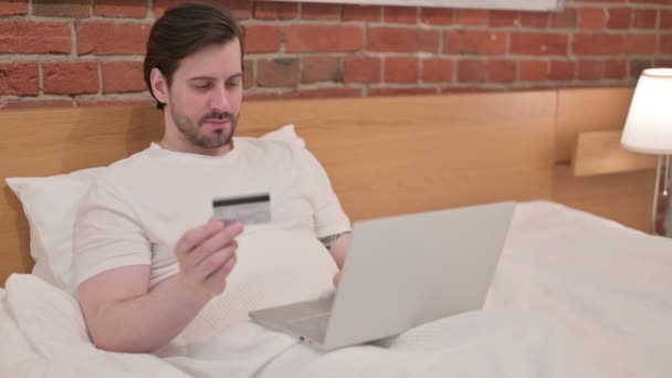 Casual giovane uomo con successo pagamento online sul computer portatile a letto — Video Stock