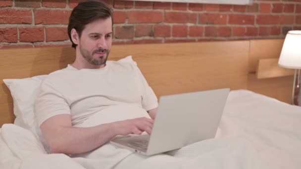 Hombre joven casual que tiene dolor de muñeca, Trabajar en el ordenador portátil en la cama — Vídeos de Stock