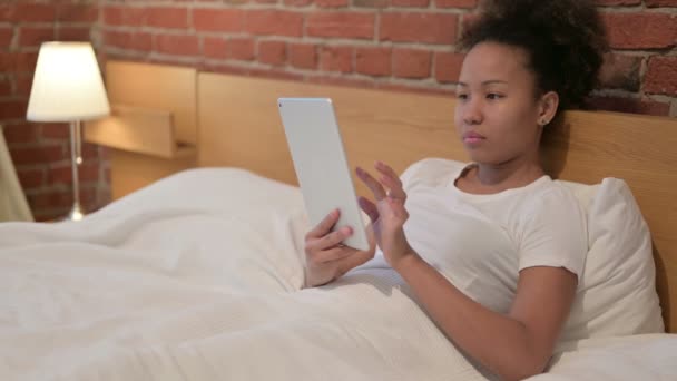 Mujer africana joven usando tableta en la cama — Vídeos de Stock