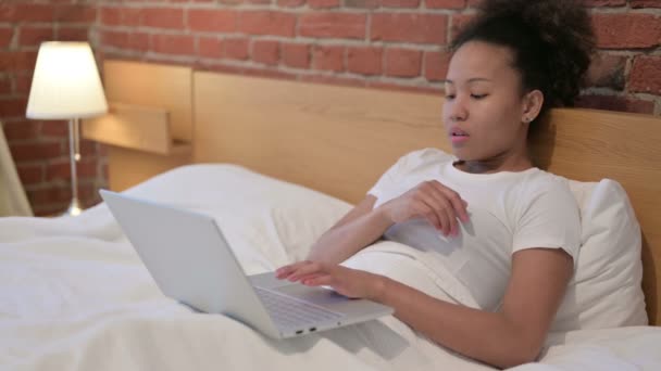 Jong Afrikaans vrouw denken en werken op laptop in bed — Stockvideo