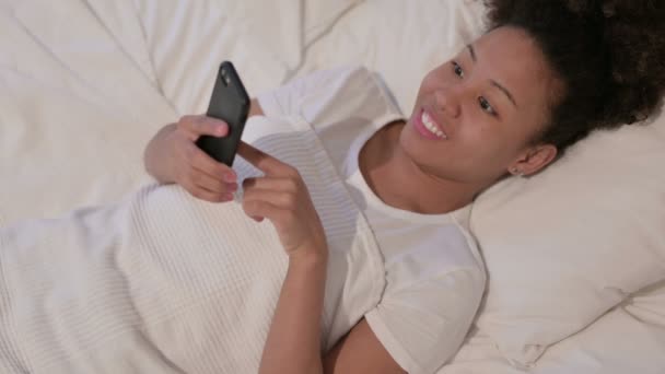 Afrikanerin feiert Erfolg auf Smartphone im Bett — Stockvideo