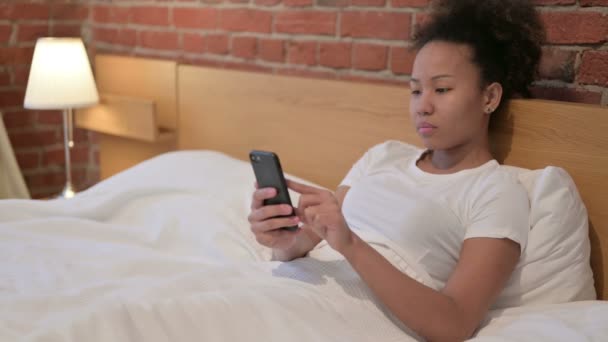 Mujer africana joven usando Smartphone en la cama — Vídeos de Stock