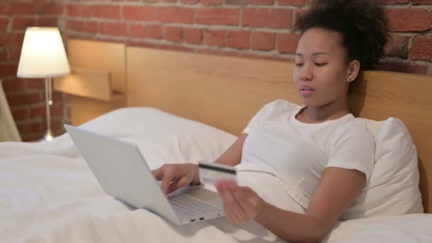 Mujer africana con éxito pago en línea en el ordenador portátil en la cama — Vídeos de Stock
