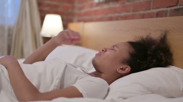 Junge Afrikanerin wacht im Bett auf — Stockvideo