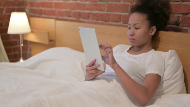 Mujer africana celebrando el éxito en la tableta en la cama — Vídeos de Stock