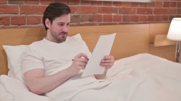 Ung affärsman Läsa dokument i sängen — Stockvideo