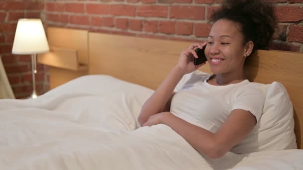 Mujer africana hablando por teléfono inteligente en la cama — Vídeos de Stock