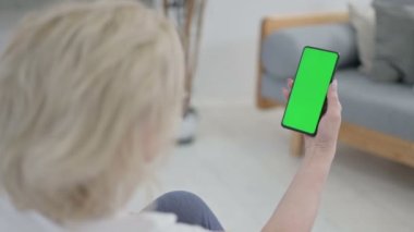 Kıdemli Yaşlı Kadın, Yoga Mat 'te Krom Anahtar Ekranlı Akıllı Telefona Bakıyor
