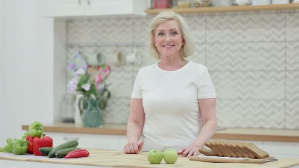 Hälsosam äldre kvinna Titta på kameran när du står i köket — Stockvideo