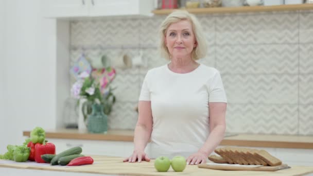 Anciana saludable sonriendo a la cámara mientras está de pie en la cocina — Vídeos de Stock