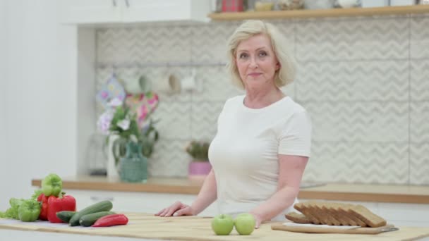 Zdravé starší žena při pohledu na kameru, zatímco stojí v kuchyni — Stock video