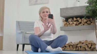Yaşlı kadın Yoga Mat 'te akıllı telefon kullanıyor.