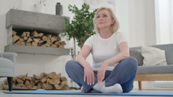 Attraktiv äldre kvinna gör Stretches på Yogamattan hemma — Stockvideo