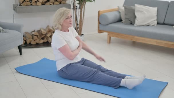 Yaşlı kadın evde yoga minderi üzerinde geriniyor. — Stok video