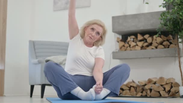 Senior gammal kvinna gör yoga på yogamattan hemma — Stockvideo