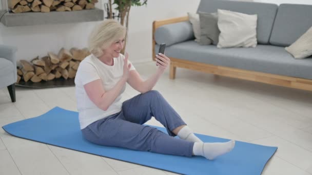 Anziana donna anziana parlando su videochiamata su smartphone mentre seduto su Yoga Mat — Video Stock