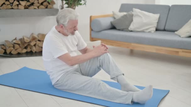 Anciano mayor teniendo dolor de rodilla en esterilla de yoga en casa — Vídeos de Stock