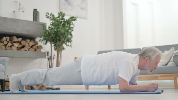 Senior alter Mann macht Plank auf Yogamatte zu Hause — Stockvideo