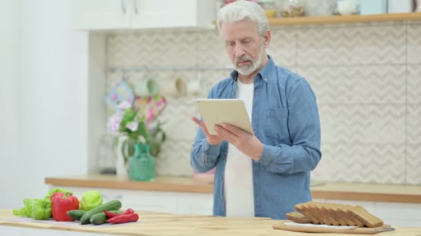 Senior oude man met behulp van Tablet terwijl Staande in de keuken — Stockvideo