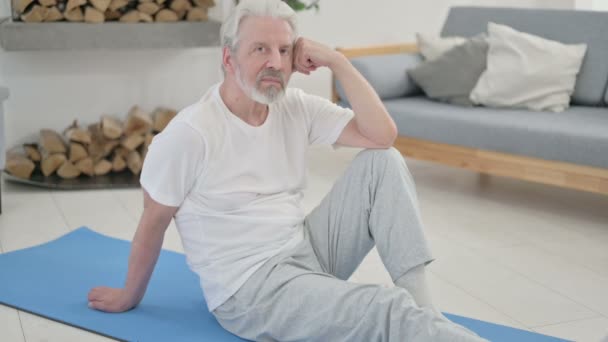 Gezond senior oude vrouw kijkend naar de camera terwijl ze op Yoga Mat zit — Stockvideo