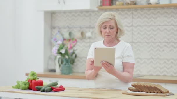 Atractiva anciana mayor usando tableta en la cocina — Vídeo de stock