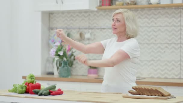 健康的老年妇女在厨房做饭的时候跳舞 — 图库视频影像