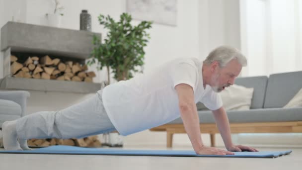 Anciano cansado haciendo flexiones en la esterilla de yoga en casa — Vídeos de Stock