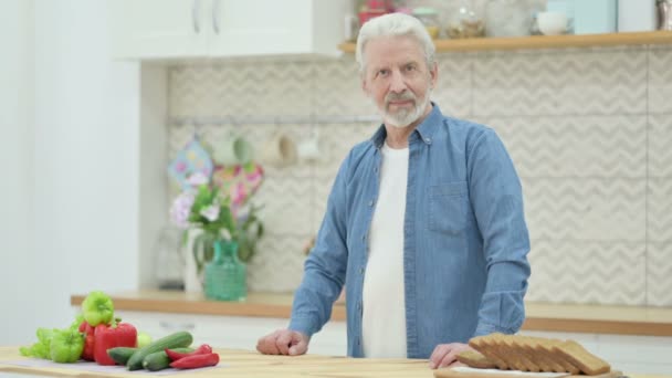 Здоровый пожилой человек показывается большой палец, стоя на кухне — стоковое видео