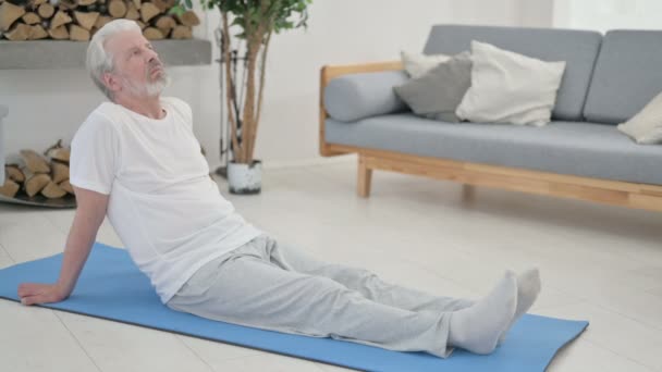 Senior alter Mann macht Yoga auf Yogamatte zu Hause — Stockvideo