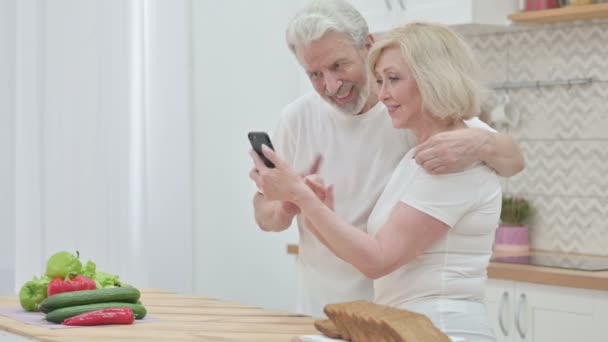 Senioren-Ehepaar nutzt Smartphone in Küche — Stockvideo