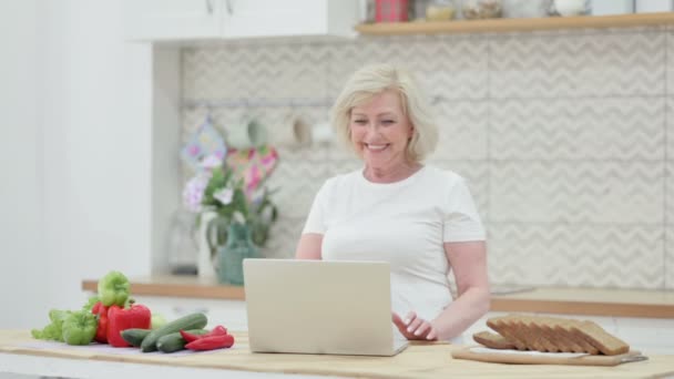 Ελκυστική ηλικιωμένη γυναίκα κάνει Video Call στο Laptop στην κουζίνα — Αρχείο Βίντεο