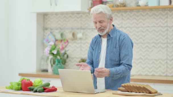 Привлекательный пожилая пара делает видео-звонок на ноутбуке на кухне — стоковое видео