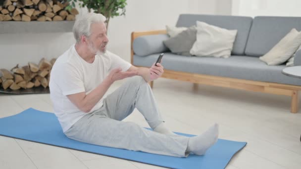 Senior Old Man talar på videosamtal på laptop medan du är på Yogamattan — Stockvideo