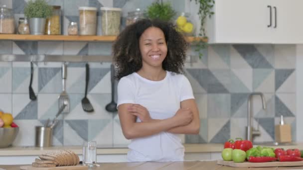 Afrikansk kvinna ler mot kameran när hon står i köket — Stockvideo