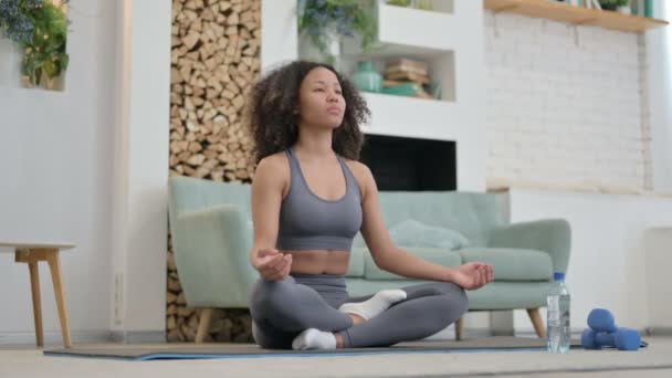 Молодая африканская женщина медитирует на коврике для йоги дома — стоковое видео