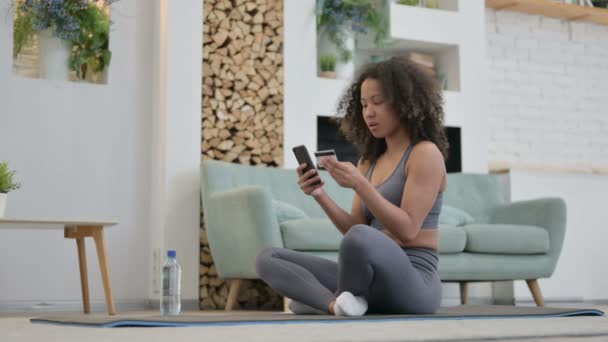 African Woman Making Online Payment on Smartphone on Yoga Mat — Stock Video