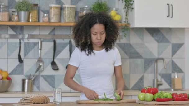 Mujer africana se siente cansada mientras corta verduras en la cocina — Vídeo de stock